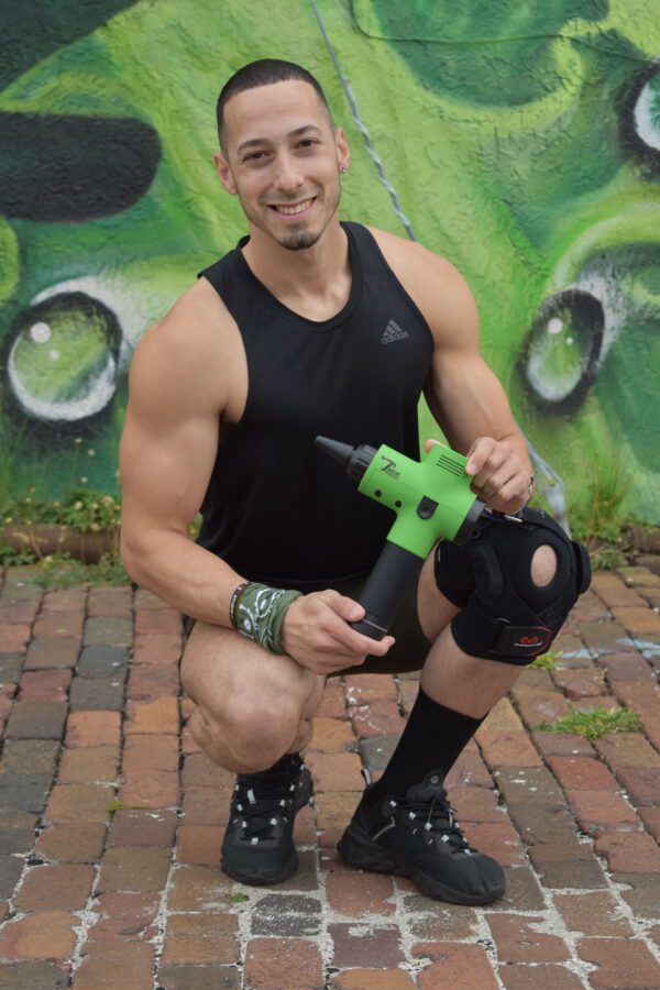 athlete holding green massage gun